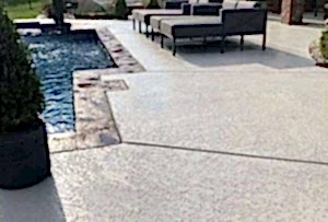 Textured pool deck with a wide outdoor couch beside the swimming pool, creating a relaxing and stylish lounging area.